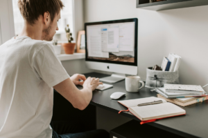 Pessoa organizando uma rotina de estudos semanal com planner, livros e laptop sobre a mesa, representando foco e planejamento.