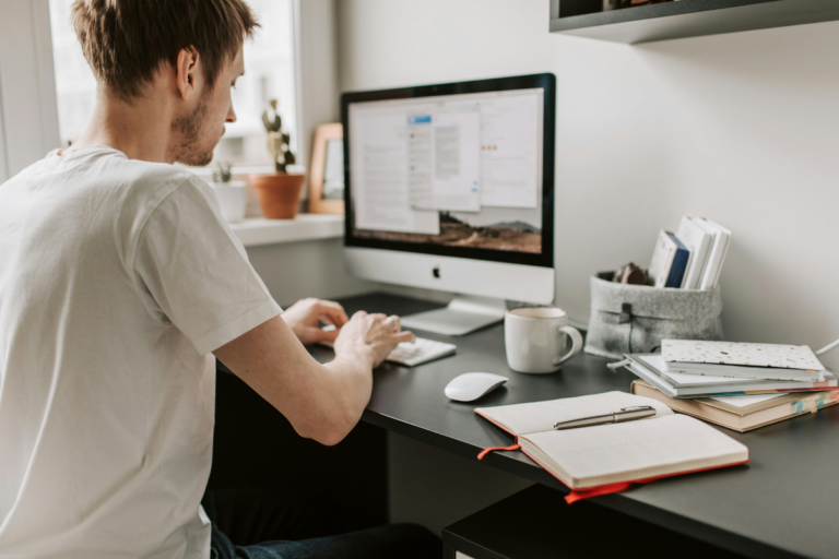 Pessoa organizando uma rotina de estudos semanal com planner, livros e laptop sobre a mesa, representando foco e planejamento.