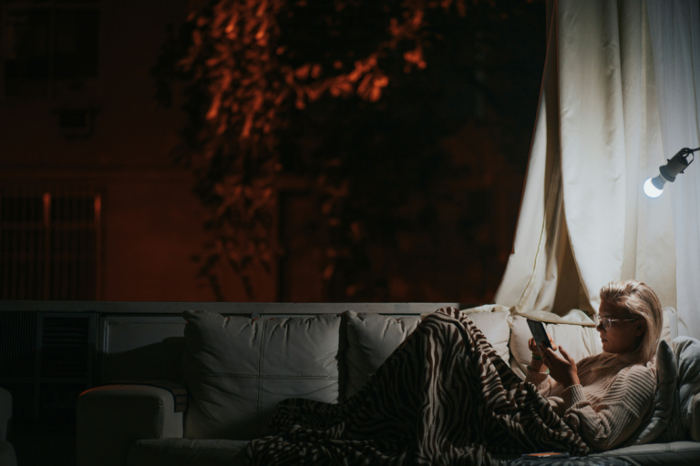 Pessoa relaxando em ambiente tranquilo à noite, com luz suave e chá natural, representando hábitos noturnos para dormir melhor.