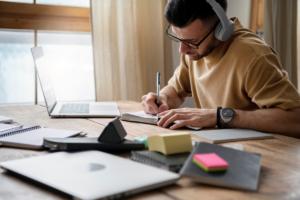Pessoa trabalhando em home office com livros e computador, aplicando técnicas de memorização e produtividade.