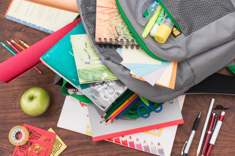 Mochilas, cadernos e materiais escolares organizados para a volta às aulas em 2025
